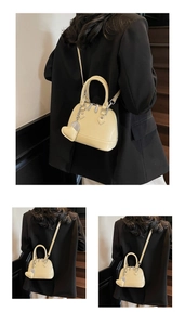 Detail of yellow shell bag with glossy finish and heart pendant on a model