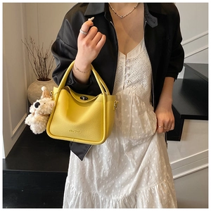 Détail du sac à main en cuir jaune avec fermoir argenté et charme en peluche