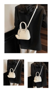 Detail view of white shell bag with glossy finish and heart charm on a vintage staircase