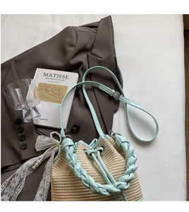 Detail of straw bucket bag with blue leather trim and pearl lace charm on dark fabric