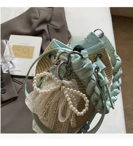 Detail of woven straw bucket bag featuring pearl bow charm and lace trim accents