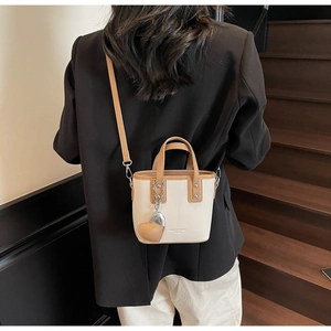 Rear view of a model styling a beige and brown mini bucket bag on wooden stairs