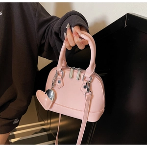 Detail of pink shell handbag featuring silver hardware and heart charm attachment
