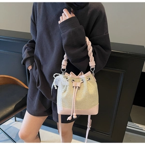 Detail of woven bucket bag with pink leather trim and elegant lace pearl charm