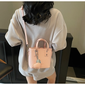 Pink bucket bag with lychee texture featuring a silver chain and heart charm detail