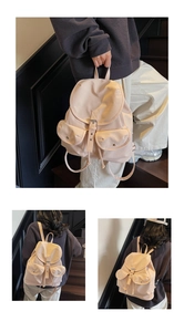 Détail du sac à dos beige crème avec rabat et deux poches frontales symétriques
