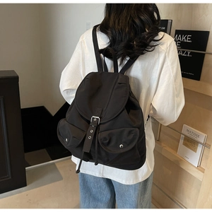 Gros plan du sac à dos rétro noir avec boucles argentées et deux poches frontales