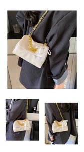 Detail of cream square bag with thick gold chain, turn-lock and pearl lace charm accessory