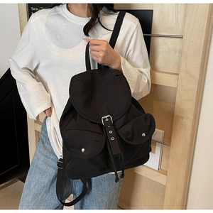 Détail du sac à dos en nylon noir avec doubles poches frontales et boucle argentée