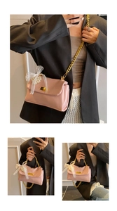 Pink crossbody bag detail with golden chain strap, lace bow and large pearl accents