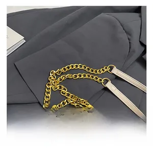 Detailed view of elegant gold metal chain and cream leather strap on a small square bag