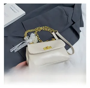Detail of square off-white leather bag with gold twist lock and pearl lace charms