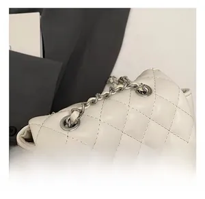 Close-up of silver metal twist lock and quilted diamond pattern on beige bag