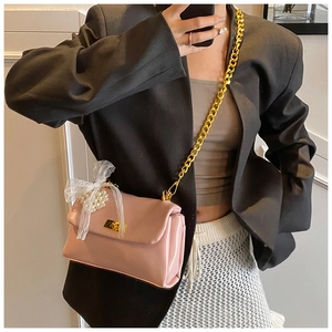 Detail of pink square crossbody bag with gold chain and lace pearl bow ornament