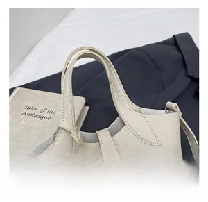 Detail of the cream leather handle with fine stitching and luxury grain texture on bucket bag