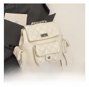 Detail showing the quilted white mini backpack with silver chain handle and metal twist lock