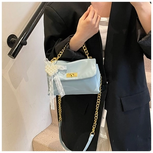 Detail of light blue square bag with gold chain, lace charm, and pearl heart accent