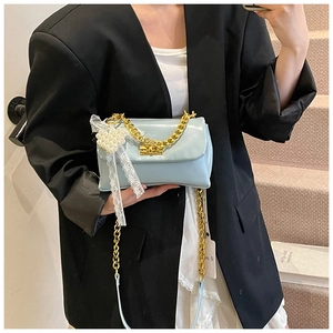 Close-up of light blue flap bag featuring golden twist lock and lace pearl pendant