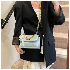 Detail shot of light blue square bag with gold chain and pearl lace charm accessory