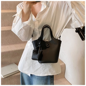 Detail shot of black litchi grain leather bucket bag with mini pouch on a model