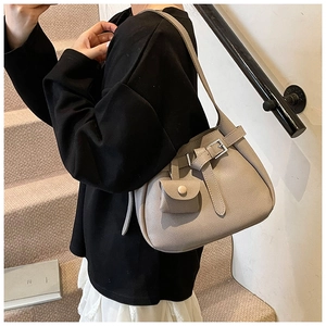 Macro view of beige lychee textured leather bucket bag with silver buckle and mini pouch
