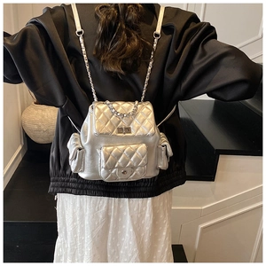 Silver quilted mini backpack with metal chain straps shown on a female model