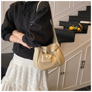 Close-up of beige lychee grain leather bucket bag with decorative mini coin purse charm