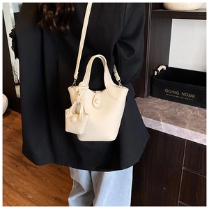 Detail of cream white lychee pattern leather bucket bag with matching mini charm