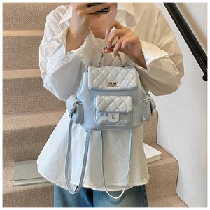 Detail view of the silver metal chain handle and quilted texture on the blue backpack