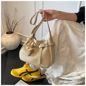 Detail view of beige pebbled leather bucket bag with silver buckle and side pocket on a model