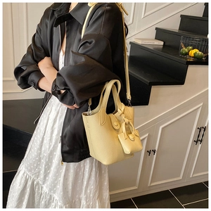 Detail showing creamy lychee texture leather bucket bag with a matching small coin purse