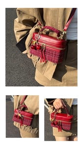 Close-up of red tweed and leather handbag with dual zippers and cherry charm detail