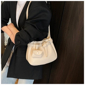 Detail of cream bucket bag with lychee texture and decorative buckle on a model
