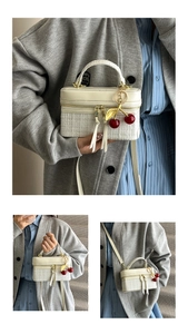 Detail of tweed box bag featuring dual gold zippers and a red cherry metal charm