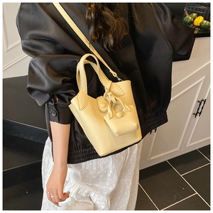 Detail of a creamy yellow lychee texture bucket bag with handle and shoulder strap