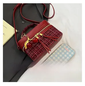 Detail of red tweed and leather crossbody bag with cherry charm on black blazer