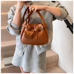 Brown lychee leather bucket bag detail with buckle and matching mini pouch accessory