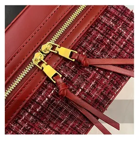 Detail of red tweed handbag featuring gold dual zippers and metallic fabric texture