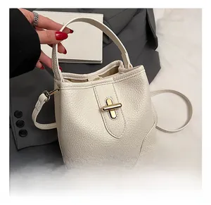 Close-up of white pebble leather bucket bag featuring gold twist lock and curved top handle