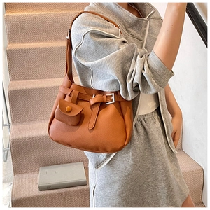 Detail of trendy orange-brown bucket bag with textured leather and mini hanging pouch