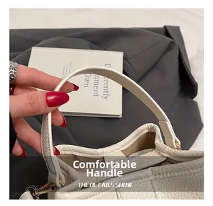Detail of comfortable handle and lychee grain leather on white crossbody bucket bag