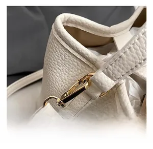 Close-up of gold metal swivel hook and cream lychee grain leather on bucket bag