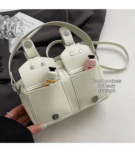 Detail of off-white multi-pocket crossbody bag showing storage capacity for small items