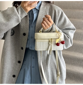 Mini cream leather and tweed handbag with cherry charm shown on indoor stairs