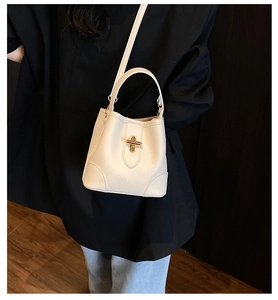 Detail of off-white lychee pattern bucket bag with golden buckle and sleek handle