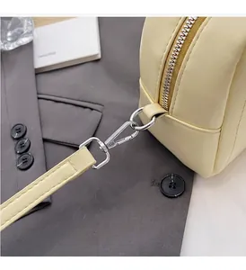 Dettaglio della ferramenta argentata e delle cuciture su una borsa giallo chiaro