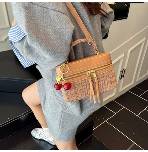 Detail of tweed and leather crossbody bag with long tassel zippers and cherry charm