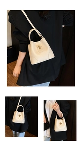 Close-up of off-white leather bucket bag with pebble texture and golden twist lock