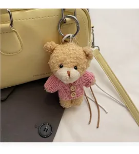 Dettaglio dell'orso di peluche con cardigan rosa su una borsa bowling gialla