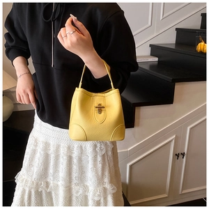 Detailed macro view of yellow bucket bag featuring lychee texture and gold metal twist lock